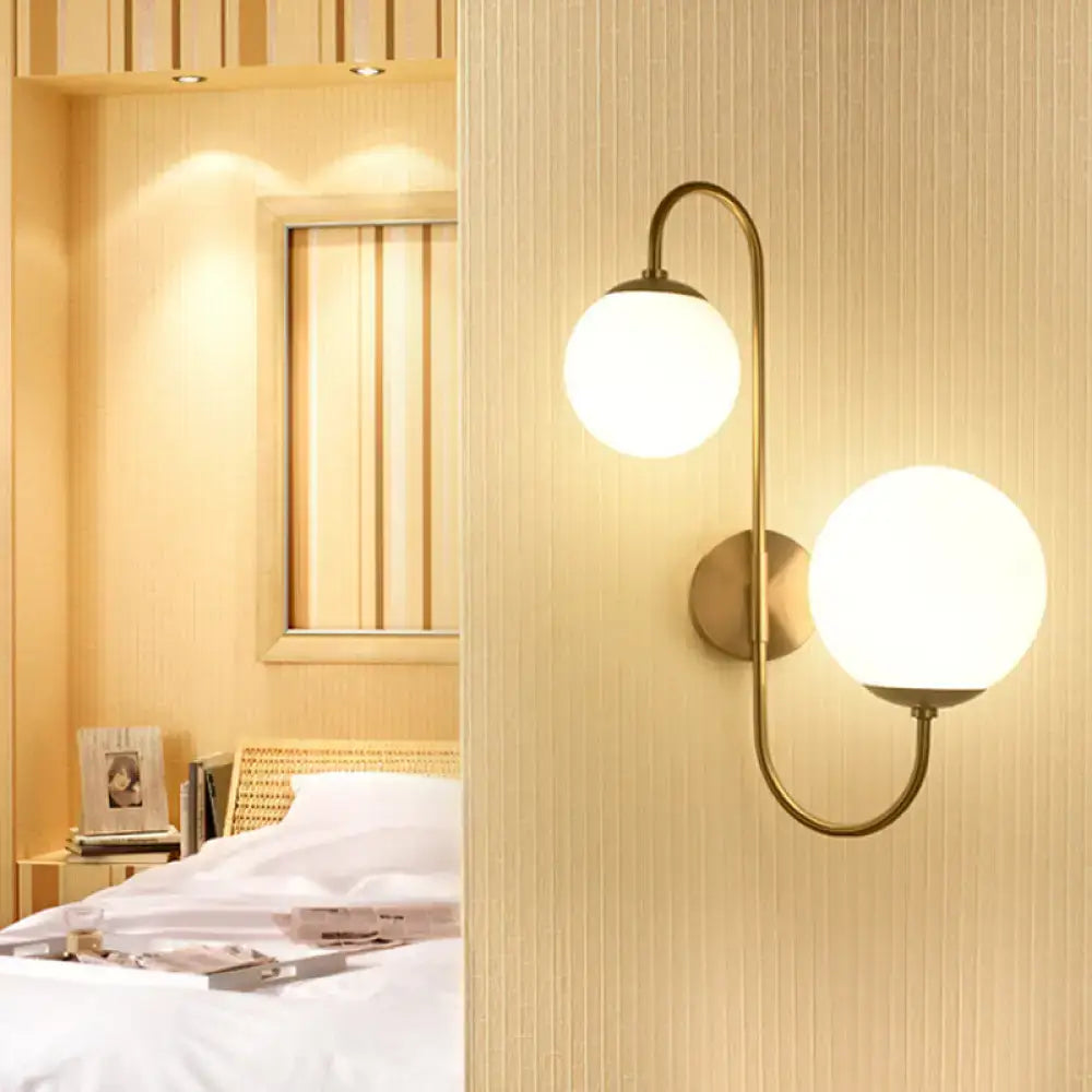 Brass-finished wall sconce light with two spherical frosted glass globes for contemporary opal glass lighting