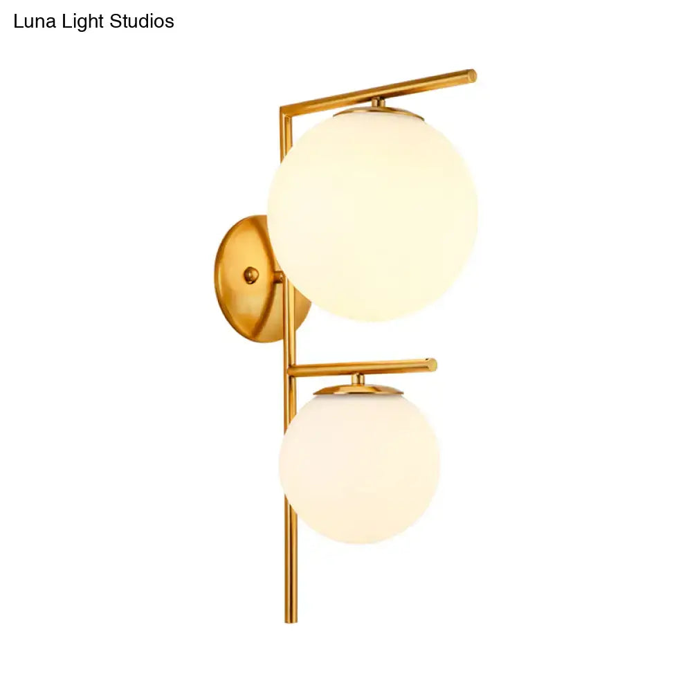 Contemporary gold light fixture bedroom sconce with gold-toned wall mount and two frosted glass globe shades shade width
