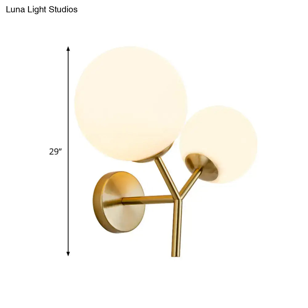 Contemporary gold light fixture with two white frosted spherical glass shades and shade width for bedroom sconce