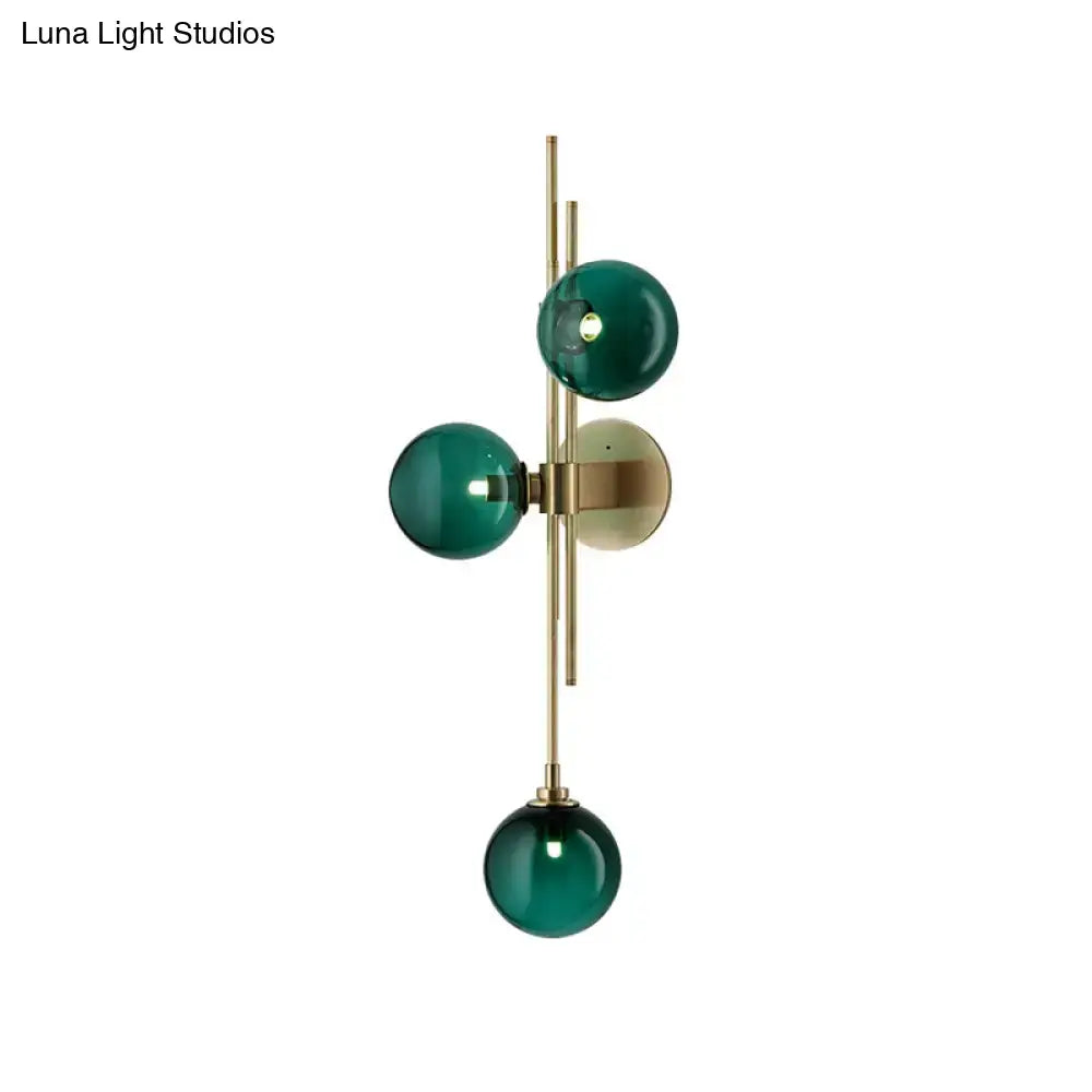 Contemporary living room wall sconce with three emerald green clear glass globes on a direct wired electric brass frame