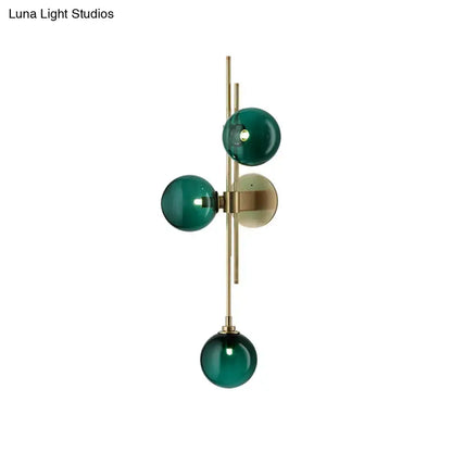 Contemporary living room wall sconce with three emerald green clear glass globes on a direct wired electric brass frame