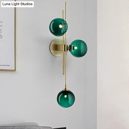 Contemporary green and clear glass globe living room wall sconce with three emerald green glass spheres on brass frame direct wired electric