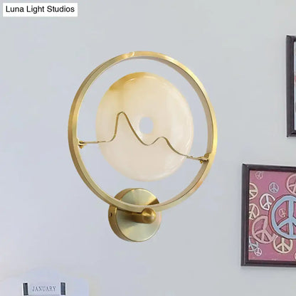 Contemporary jade and gold ring wall lamp with gold-toned circular wall mount and amber glass shade for bedroom