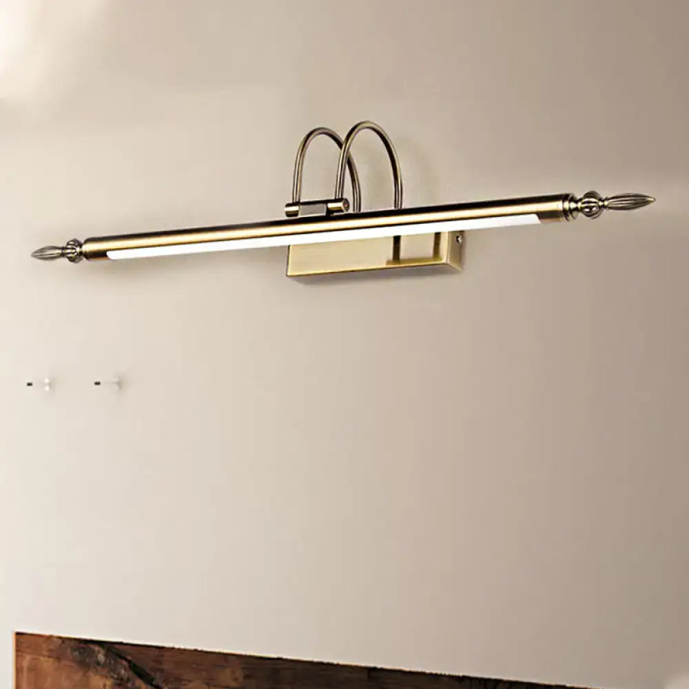 A sleek brushed brass wall-mounted vanity light with warm light and ornate curved finials for bedroom use