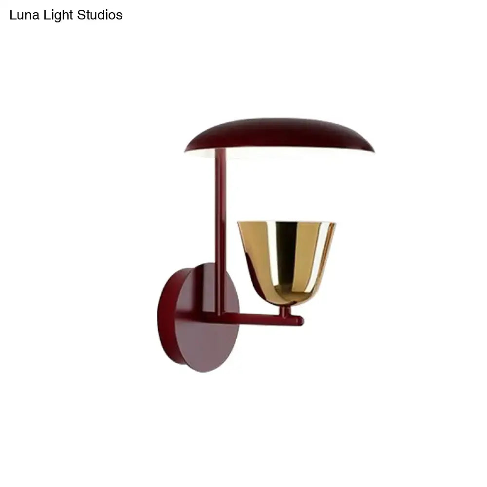 Contemporary wall-mounted light bedroom sconce with deep red metal frame and polished brass bell-shaped lampshade