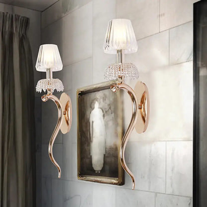 Contemporary rose gold wall sconce with gold-toned arms crystal embellishments and clear ribbed glass shade for bedroom lighting