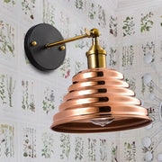 Contemporary rose gold ribbed design wall sconce with copper tones brass accents and black mounting plate for bedroom use