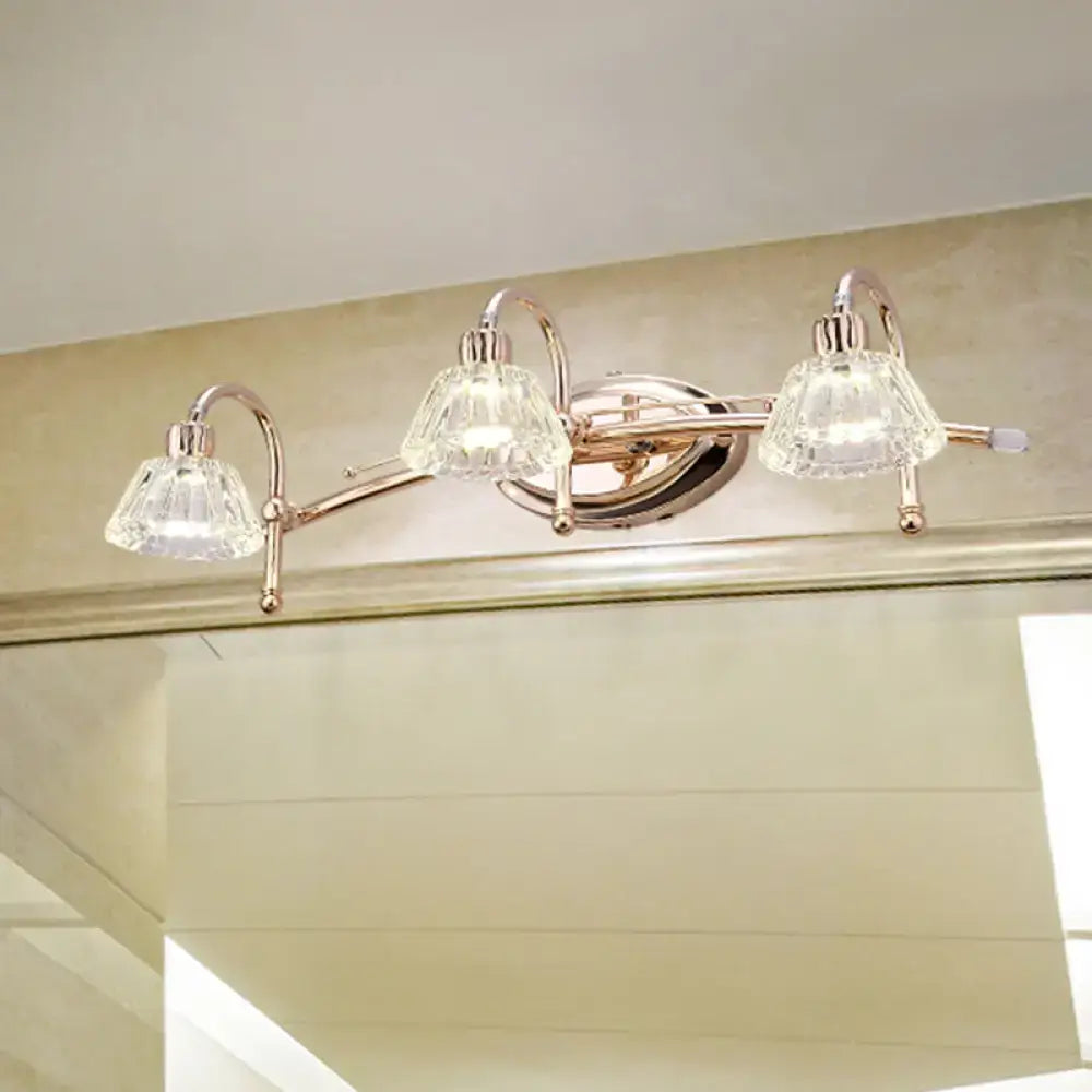 Contemporary rose gold wall vanity light with brass finish three-light fixture and truncated cone faceted crystal shades