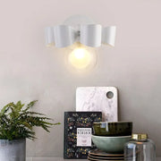 Contemporary white ceramic wall lamp with sculpted petal design and clear glass round wall element for bedroom use