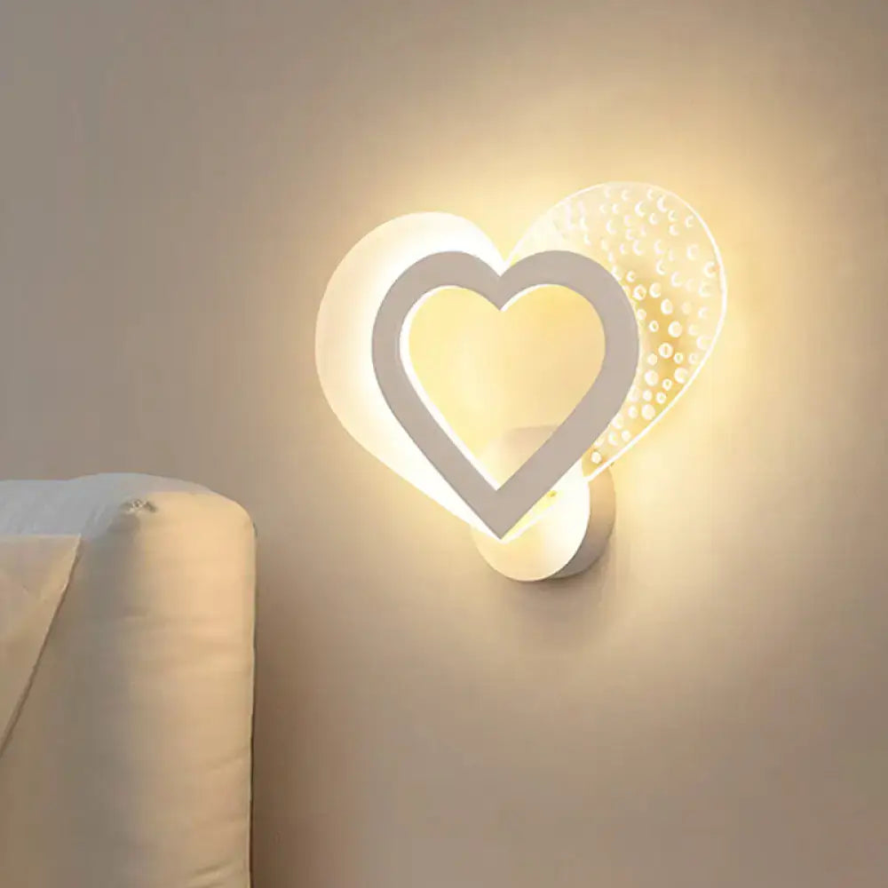 A modern white love heart wall mounted light with glowing textured glass panel and illuminated inner frame for bedrooms