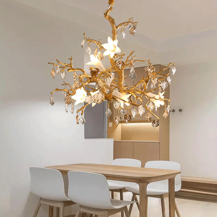Copper branch chandelier featuring a golden tree branch design with white flowers and clear crystal pendants
