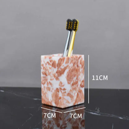 A square coral pink marble bathroom toothbrush holder with white accents holding two toothbrushes from decorbites coral pink set
