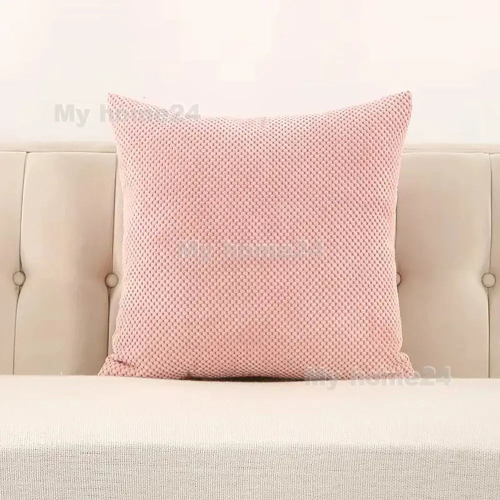 A soft pink corduroy corn kernel throw pillow with woven knit texture on beige tufted sofa for decorbites corduroy corn decor