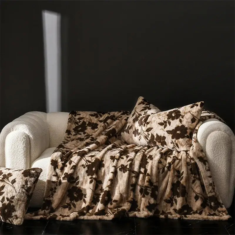 Cream-colored cosy faux rabbit plush throw blanket with dark brown floral pattern draped over off-white sofa decorbites cosy faux