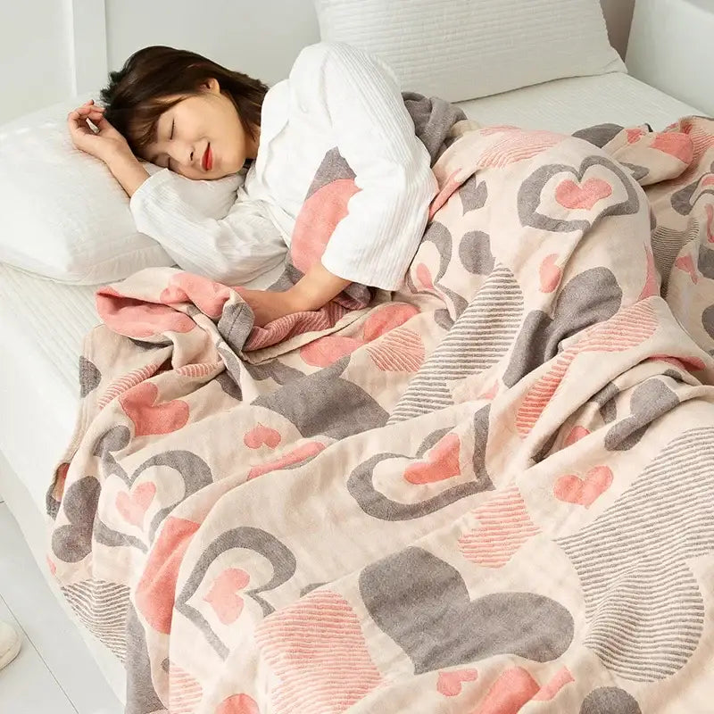 A soft pastel pink and gray heart-patterned cotton gauze boho throw with plush texture for decorbites cotton gauze collection