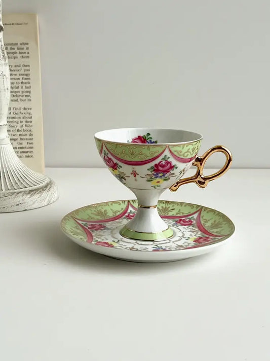 A delicate court style latte porcelain cup set with gold handle and pink green floral design on matching saucer