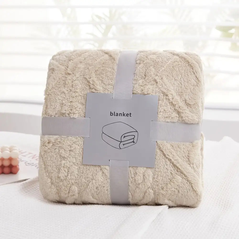 A cream-colored plush blanket with a soft textured surface wrapped in gray ribbon from decorbites cozy jacquard