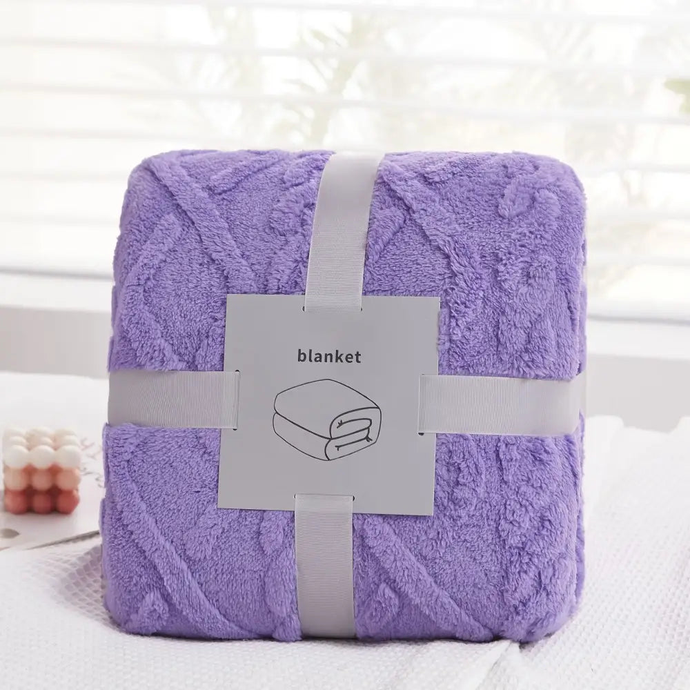 A plush lavender decorbites cozy jacquard blanket with textured cable knit pattern wrapped in white ribbon labeled blanket
