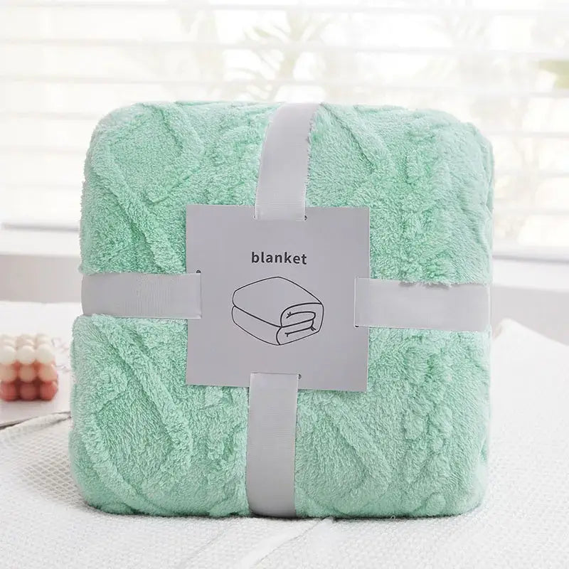 A soft mint green plush blanket with textured looped surface tied with white ribbon for cozy jacquard plush decorbites