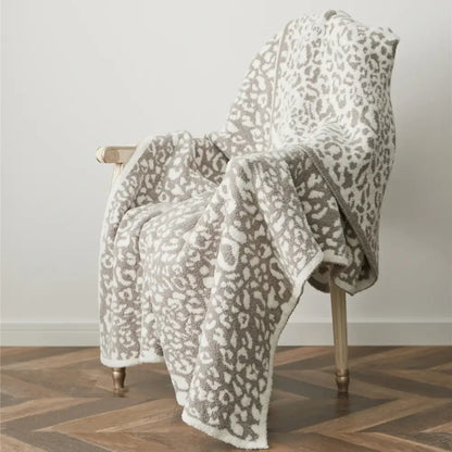 A plush cream and gray leopard print knitted throw blanket with a soft textured surface perfect for cozy leopard decorbites