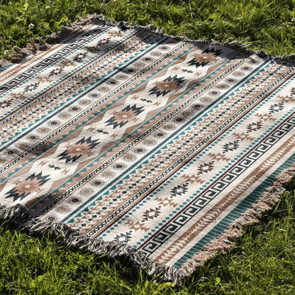 A cozy nordic camping woven throw blanket in cream with beige teal and black geometric pattern and fringed edges for decorbites cozy nordic