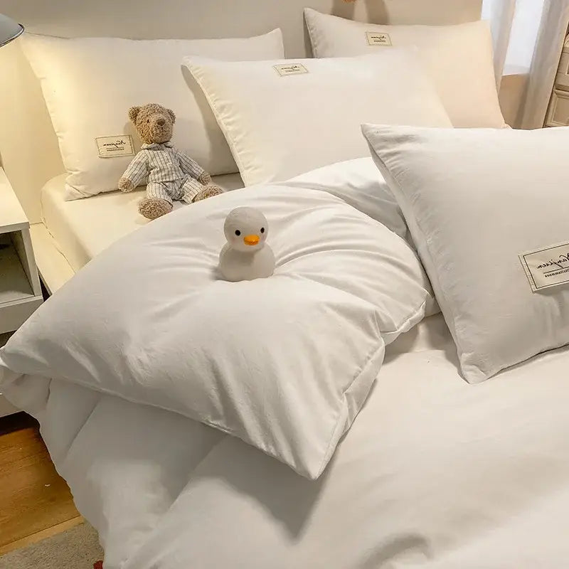 White plush duck toy with orange beak on a white duvet featuring decorbites cozy plaid duvet cover blue and white bedroom bedding set