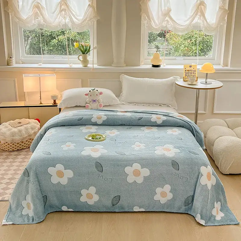 A soft light blue fleece blanket with colorful flower patterns of white daisies and green leaves for bedroom decor