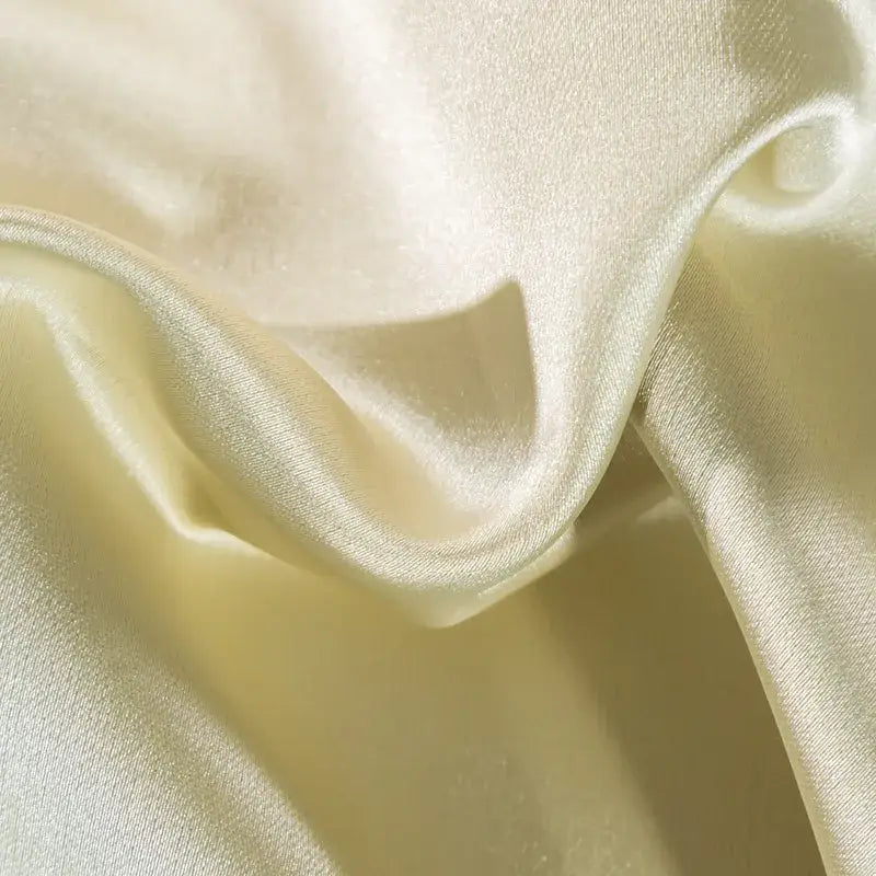 Cream-colored satin fabric with a smooth finish and gentle folds in a 200s embroidery Egyptian cotton bedding set