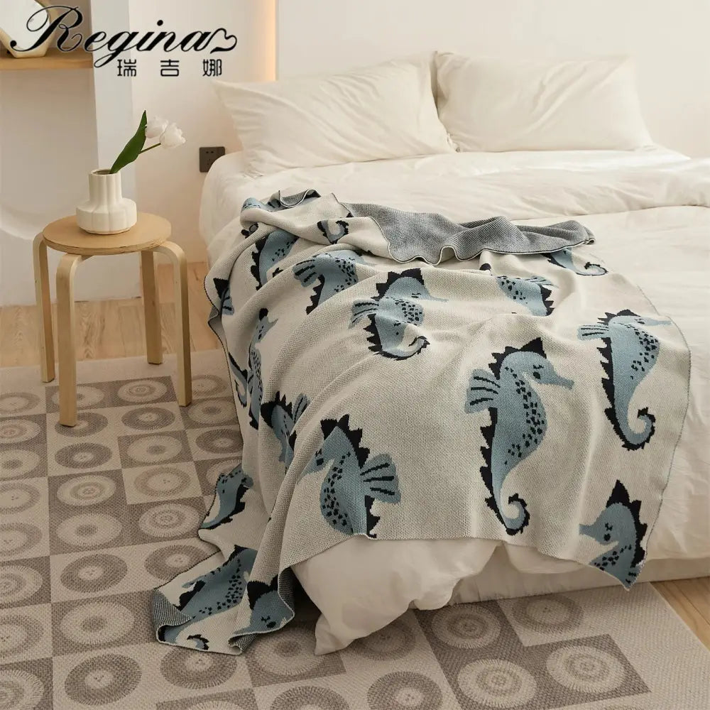 Cream and blue cute sea horse cotton knitted throw blanket with soft cream base and playful seahorse pattern