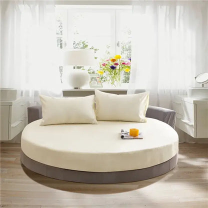 Cream and gray fitted bed sheet set on a cream circular fitted bed with gray base and two matching pillows