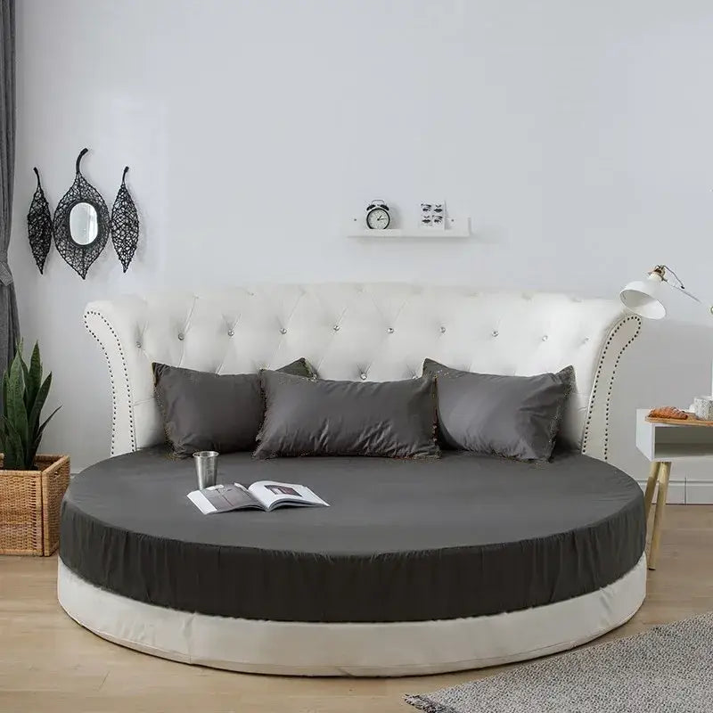 Round fitted bed with tufted white headboard and cream and gray bed sheet set for elegant bedroom decor