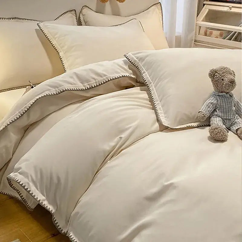 Cream-colored satin bedding set with subtle black zigzag stitching and cozy shell edges from decorbites cozy shell