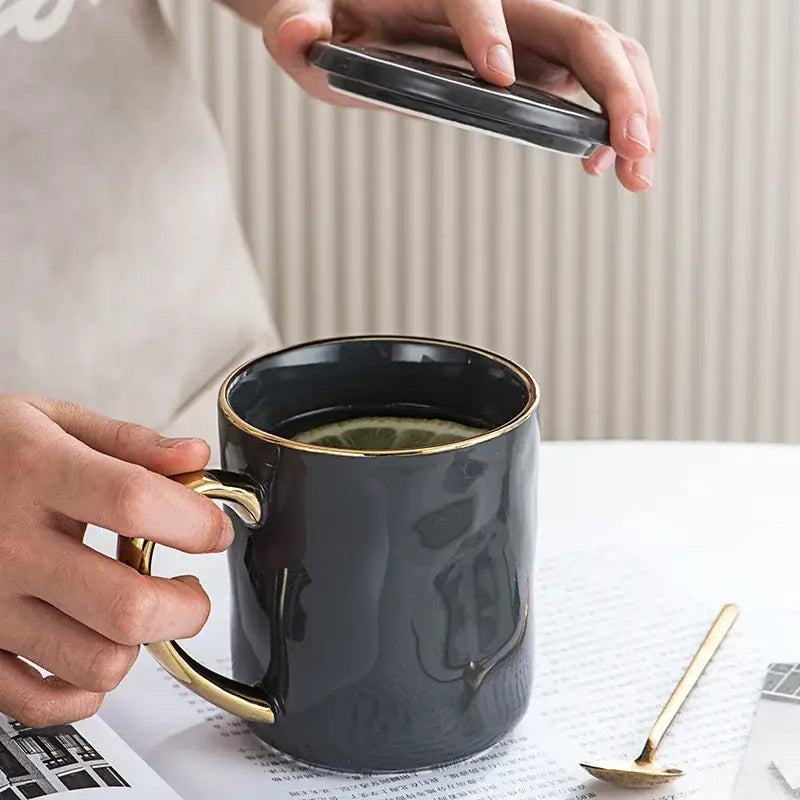 Black ceramic gold rim mug with matching lid being lifted hands from nordic gold rim mug set for kitchen use