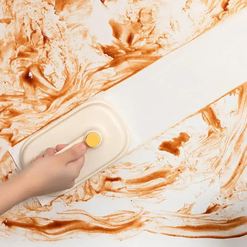 A beige scraper with yellow circular handle used for kitchen cleaning with cream and yellow silicone cleaning brush