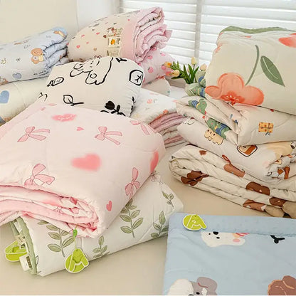 Stack of cream pastel quilted comforters with decorbites cartoon pattern summer design featuring bows hearts and animals