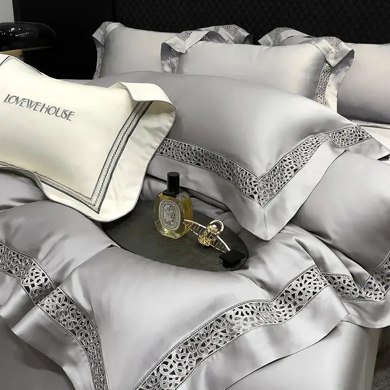 Silver satin pillowcases with intricate lace trim and embroidered lovehouse branding in cream eucalyptus lyocell 1000tc bedding set