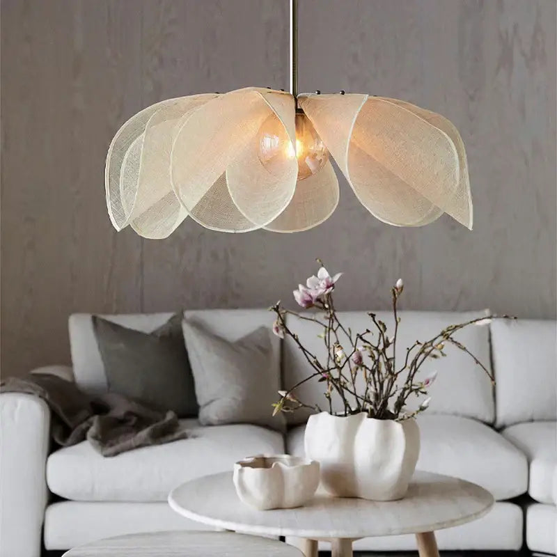 Cream fabric flower chandelier with layered petal-like shades suspended from a slender metallic rod for dining room