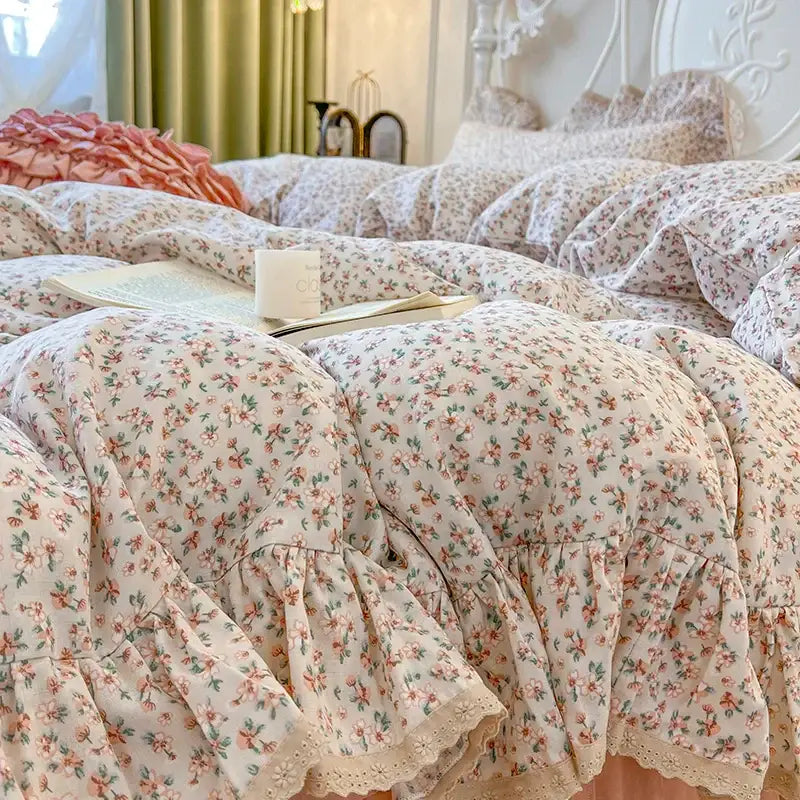 Cream-colored bedding set with double layer lace ruffles, delicate pink and green floral patterns, and lace-trimmed hem