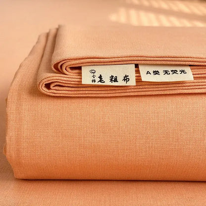 A neatly folded peach-colored cotton bed cover with textured weave and white labels for decorbites cooling cotton