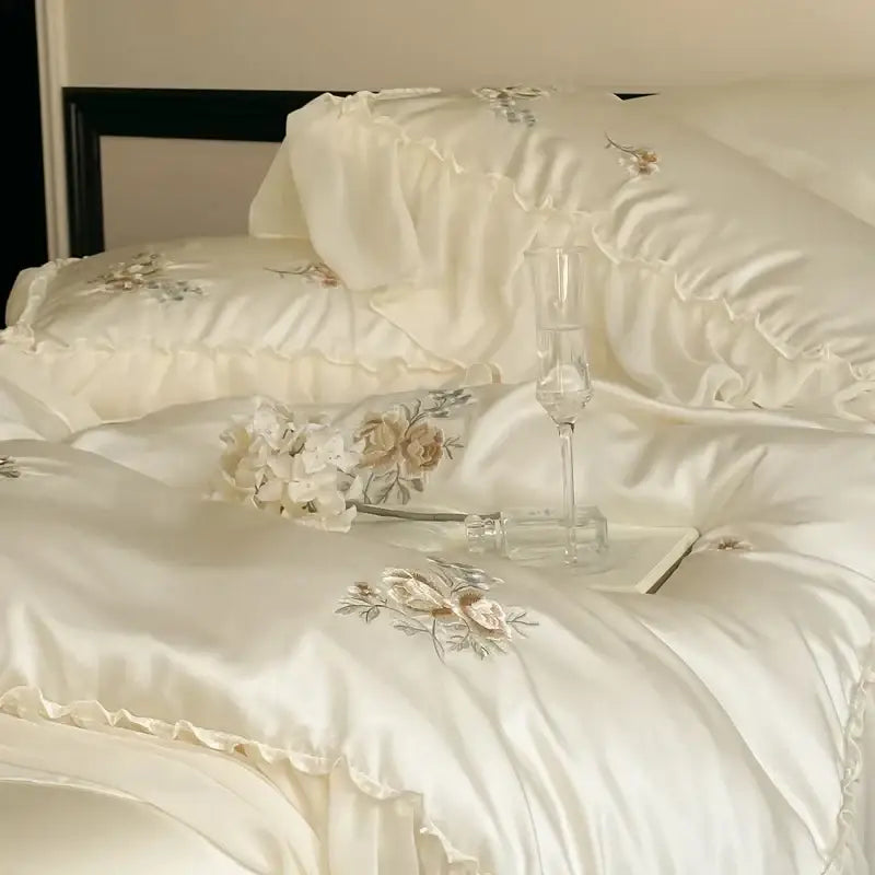 Cream-colored satin bedding set with delicate decorbites flowers embroidery and lace ruffles for elegant bedroom decor