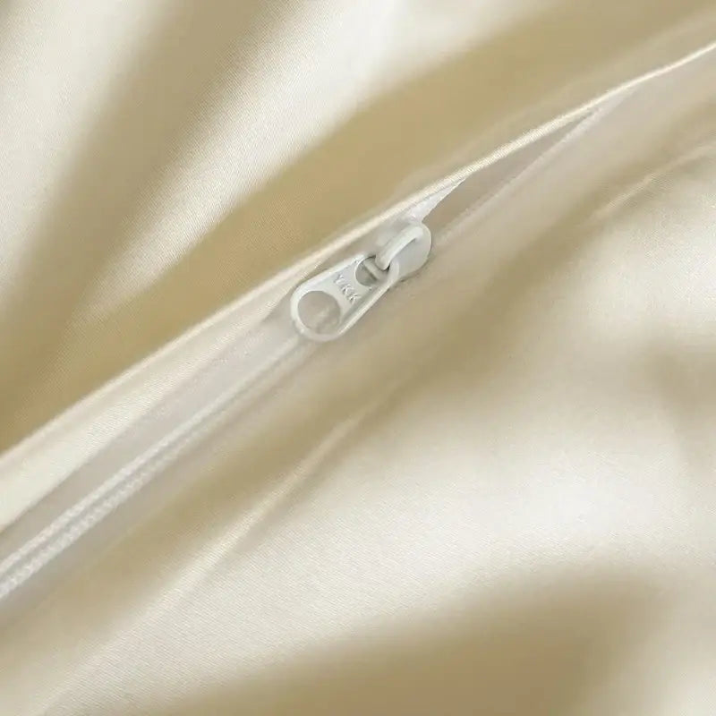 Cream-colored satin bedding set with lace ruffles and decorbites flowers embroidery featuring a white zipper pull