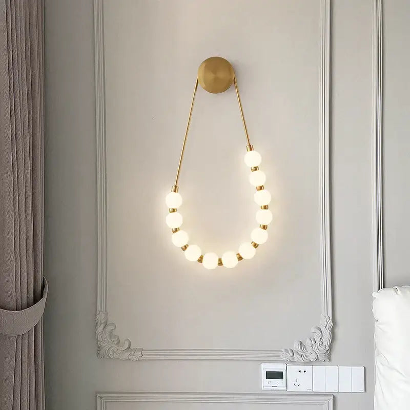 Gold-toned wall lamp with warm glowing spherical bulbs in a cream italian style decorbites globe bedroom sconce
