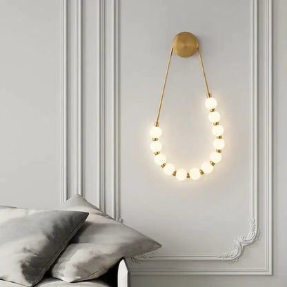 Gold-toned cream italian style wall lamp with glowing spherical bulbs in an elegant curved pendant design for bedroom decorbites