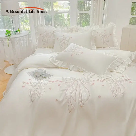 Cream-colored ice silk duvet set with embroidered ruffles featuring delicate bows and pink floral accents for bedroom bedding