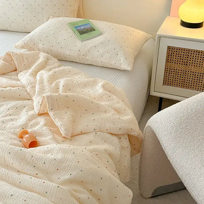 Cream polka dot floral quilt set featuring a cream-colored muslin blanket with subtle polka dots draped over bed
