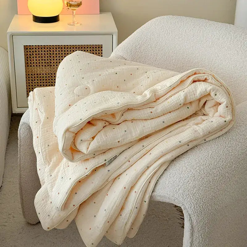 Cream polka dot floral quilt set featuring a soft cream quilted blanket with subtle polka dot pattern on white chair