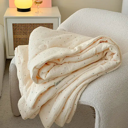 Cream polka dot floral quilt set featuring a soft cream quilted blanket with subtle polka dot pattern on white chair