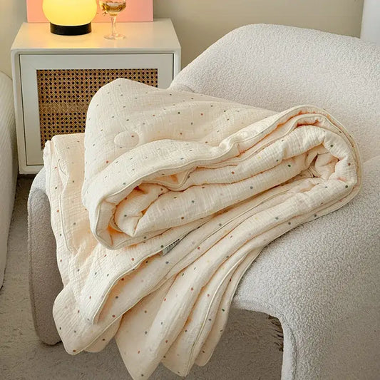 Cream polka dot floral quilt set featuring a soft cream quilted blanket with subtle polka dot pattern on white chair