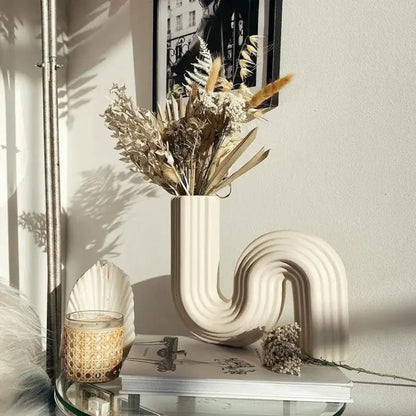 Cream ribbed geometric ceramic vase with a sleek curved design for living room decor by Decorbites geometric ceramic