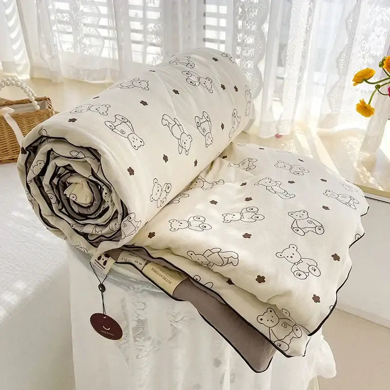 A cream teddy bear breathable double gauze quilt with black bear outlines and brown flowers for bedroom bedding